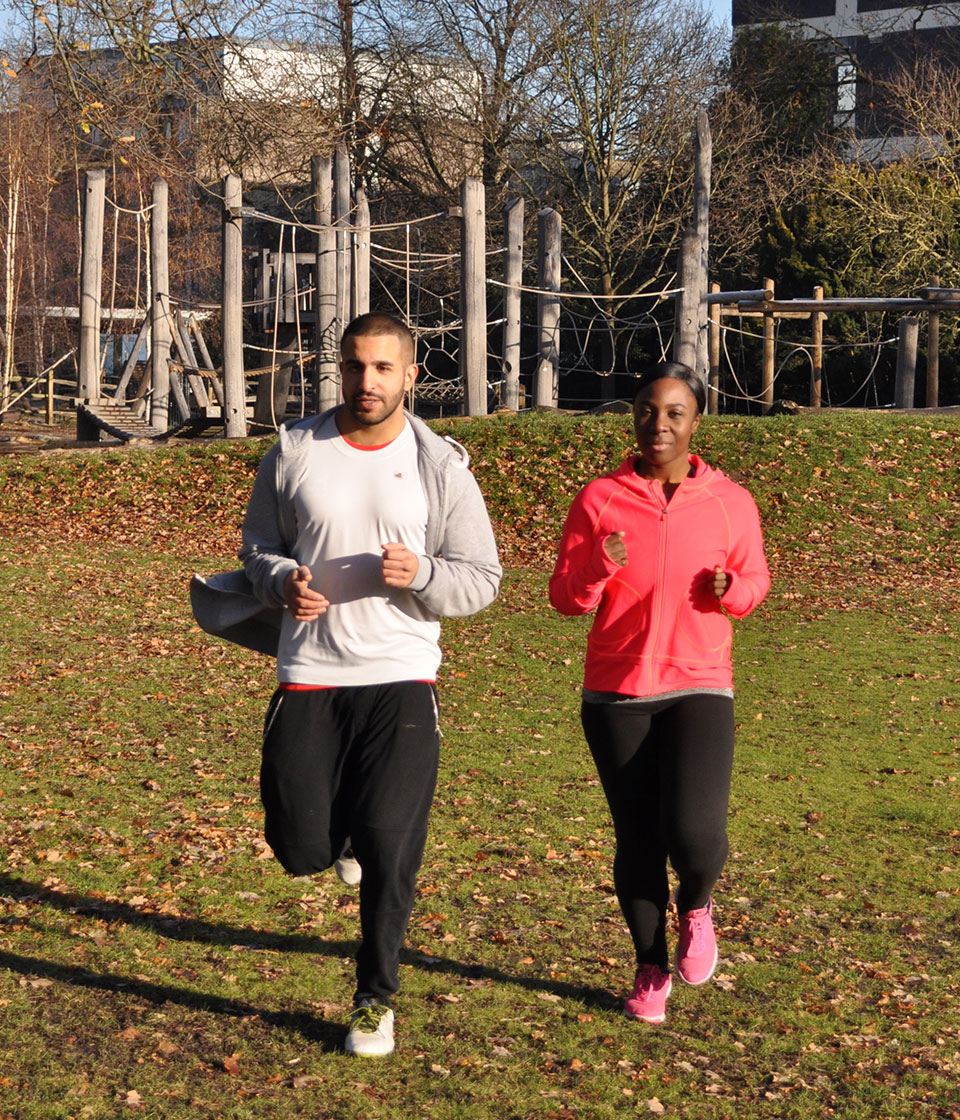 A male and female jogging in a park to keep fit